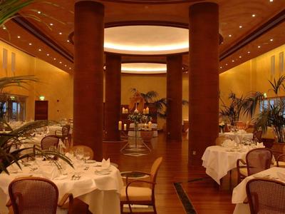 Elegantes Restaurant mit runden Marmortischen, braunen Stühlen und warmem, gelblichen Licht.