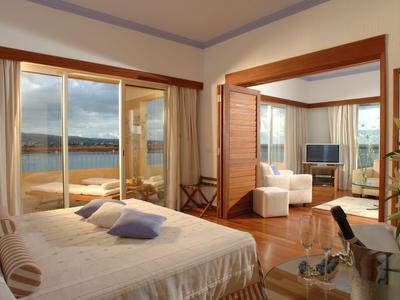 Helles Hotelzimmer mit Doppelbett und Terrasse mit Meerblick