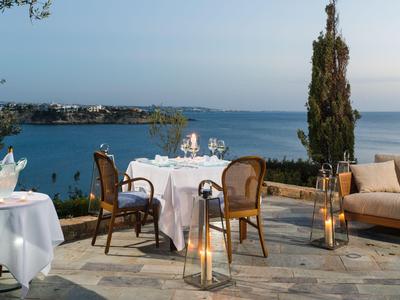 Terrasse mit gedecktem Tisch, Stühlen und Sofa mit Blick auf das Meer bei Sonnenuntergang.