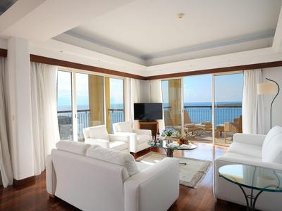 Modernes Hotelzimmer mit weißer Einrichtung und Panoramablick auf das Meer.