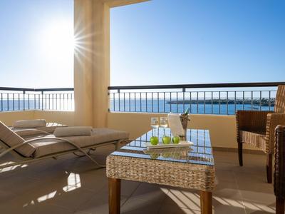Sonnige Hotelterrasse mit gemütlichen Lounge-Möbeln und Meerblick.