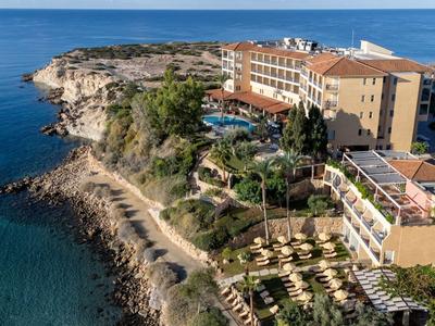 Hotel auf einer felsigen Klippe mit Meerblick und Gartenanlagen neben dem Wasser.