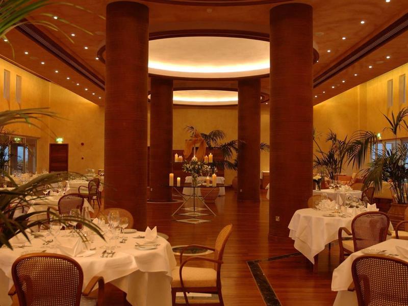 Elegantes Restaurant mit runden Marmortischen, braunen Stühlen und warmem, gelblichen Licht.