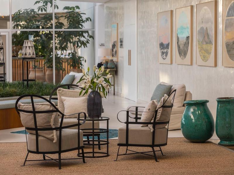 Gemütliche Sitzecke mit Polstersesseln, schwarzem Metallgestell und großen grünen Vasen.