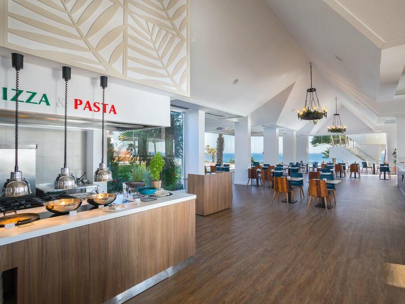 Großer, heller Speisesaal mit Pizza- und Pasta-Station und modernen Holzmöbeln.