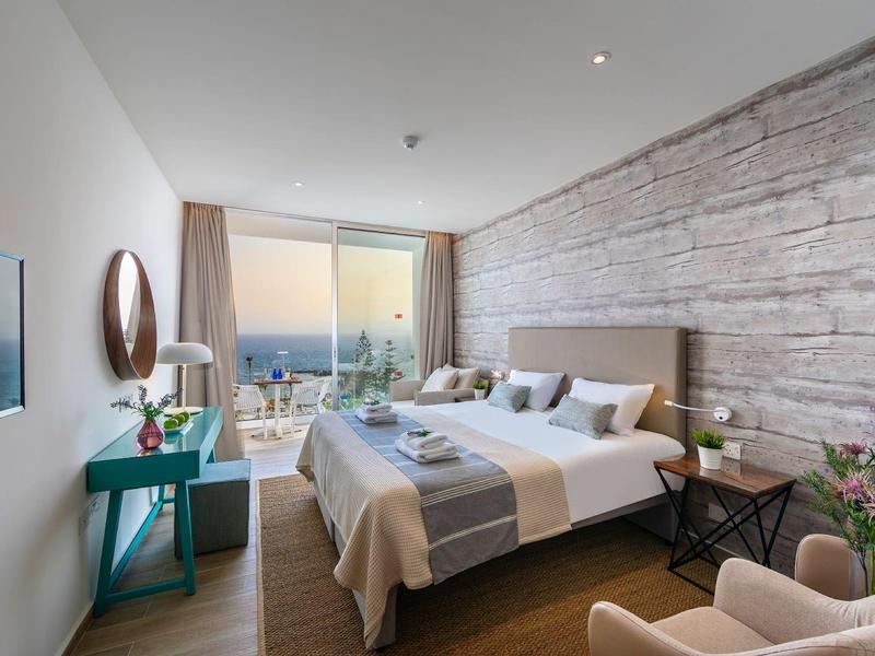 Modernes Schlafzimmer mit großem Bett, Steinwand, türkisfarbenem Schreibtisch und Panoramafenster.