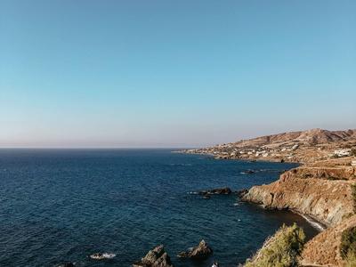 Küste mit felsigem Ufer und klarem blauem Meer unter blauem Himmel, geeignet für Urlaub.