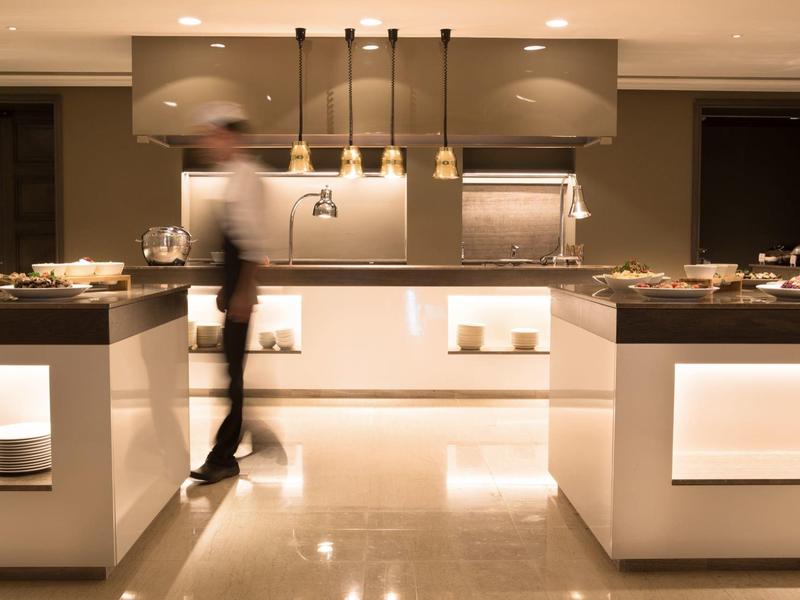 Moderne Restaurantküche mit warmem Licht, glänzendem Boden und verschwommenem Koch in Bewegung.