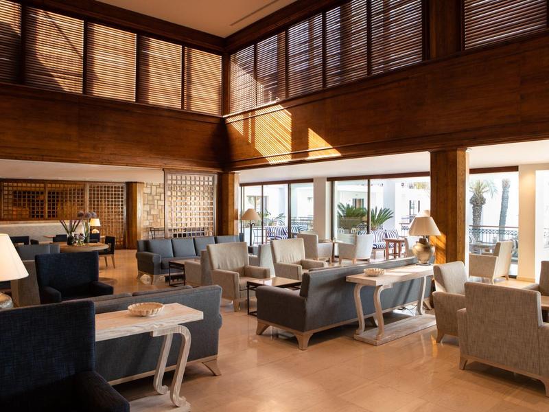 Hell eingerichteter, moderner Lounge-Bereich mit großen Fenstern, Holzelementen und bequemen Sesseln.