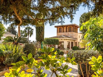 Une maison de style méditerranéen entourée d'un jardin luxuriant avec diverses plantes et arbres.