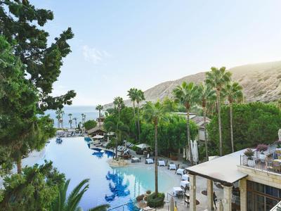 Zone de piscine luxueuse avec palmiers et collines en arrière-plan dans un cadre de vacances.