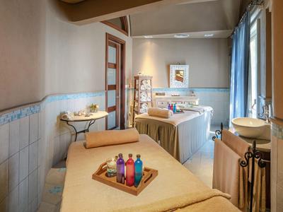 Ein heller Wellnessraum mit entspannter Atmosphäre, Massageliegen und bunten Aromaölen.