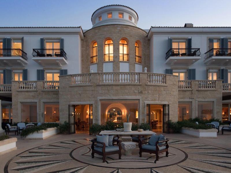 Elegantes Hotelgebäude mit großer Terrasse, Beleuchtung und stilvoller Sitzgruppe am Abend.