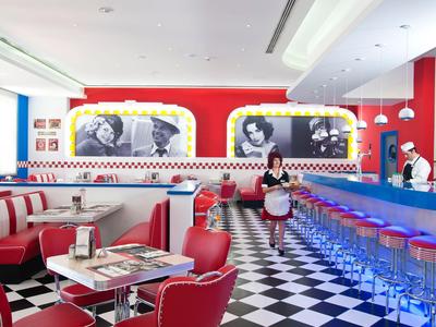 Retro-Diner mit rot-weißen Sitzbänken, blauem Barbereich und schwarz-weiß kariertem Boden.