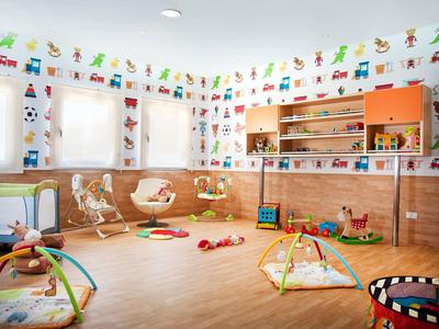 Heller Spielraum mit bunten Wänden, Holzmöbeln und verschiedenen Spielsachen auf hellem Boden.