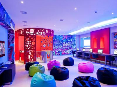 Bunt gestalteter Raum mit Sitzsäcken, Computern an Tischen und leuchtender Deckenbeleuchtung.