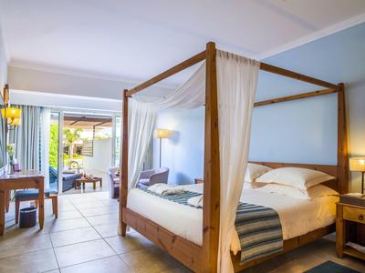 Helles Schlafzimmer mit Himmelbett aus Holz, blauen Wänden und Zugang zu Terrasse.