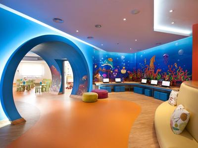 Bunter Kinderraum mit blauem Meermotiv, runden Türen, Sitzbänken und bunten Sitzwürfeln.