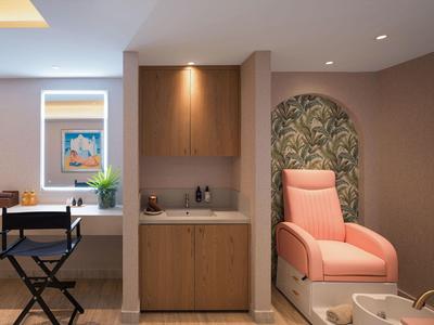Nowoczesny pokój spa z fotelem do pedicure, umywalką i drewnianymi szafkami w stonowanych tonach.