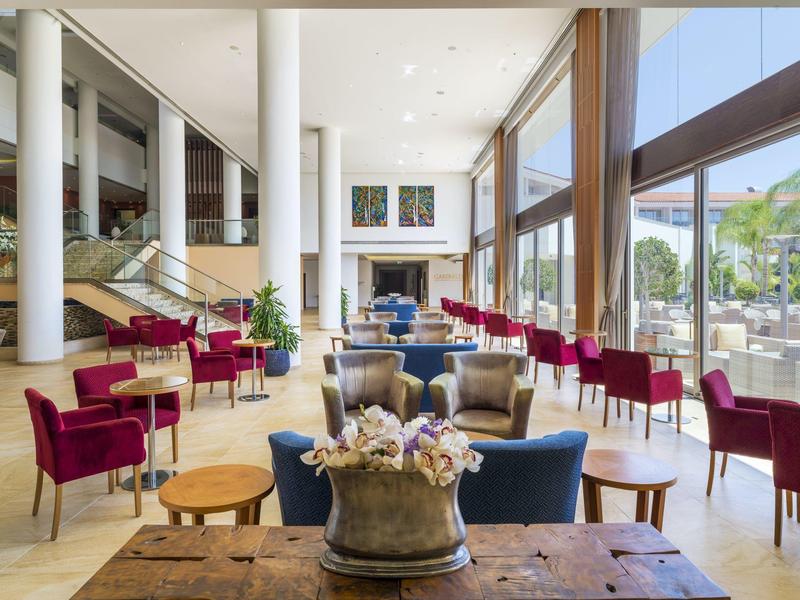 Großer heller Raum mit bodentiefen Fenstern, roten Stühlen und blauen Sofas, moderne Dekoration.