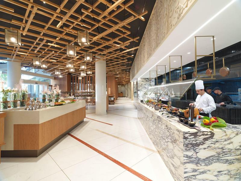 Moderner Restaurant-Innenraum mit Holzgitter-Decke, Marmor-Theke und Koch in weißer Kleidung.