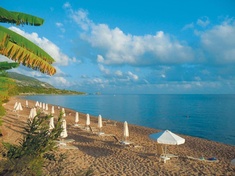 Ein ruhiger Strand mit weißen Sonnenschirmen, blauem Himmel und leicht bewölkter Atmosphäre.