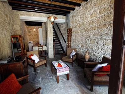 Gemütlicher Hotel-Wohnbereich mit Steinwänden, Holzmöbeln und Treppe im Hintergrund.