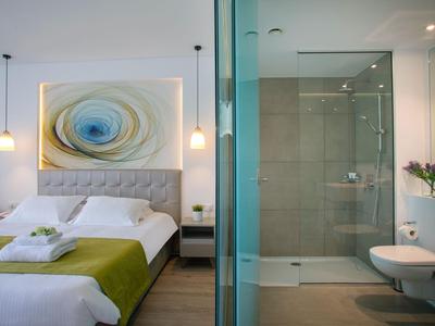 Modern bedroom with double bed and adjacent bathroom with glass shower.