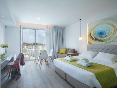 Modern hotel room with double bed, desk, and city view.