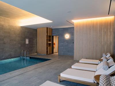 Modern indoor pool area with comfortable loungers and ambient lighting in a hotel.