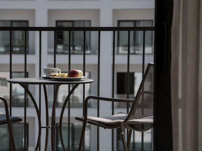 A round table with two chairs on a balcony with buildings in the background.