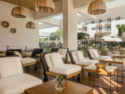 Open hotel area with wooden furniture, white cushions, and decorative wall clocks.