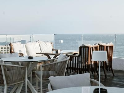 Balcony with white furniture offers sea view and a relaxed atmosphere at a hotel.