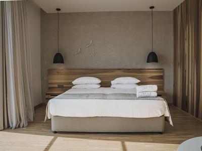 Modern hotel room with large bed, wooden headboard, and two bedside lamps.