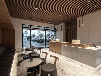 Modern hotel reception area with wooden ceiling, marble counter, and seating.