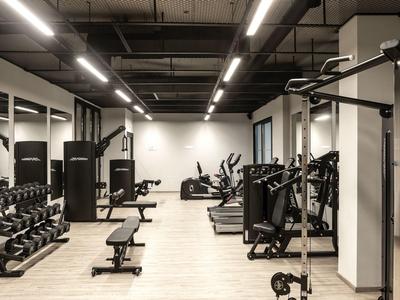 Modern, well-equipped gym with machines and dumbbells in a hotel setting.