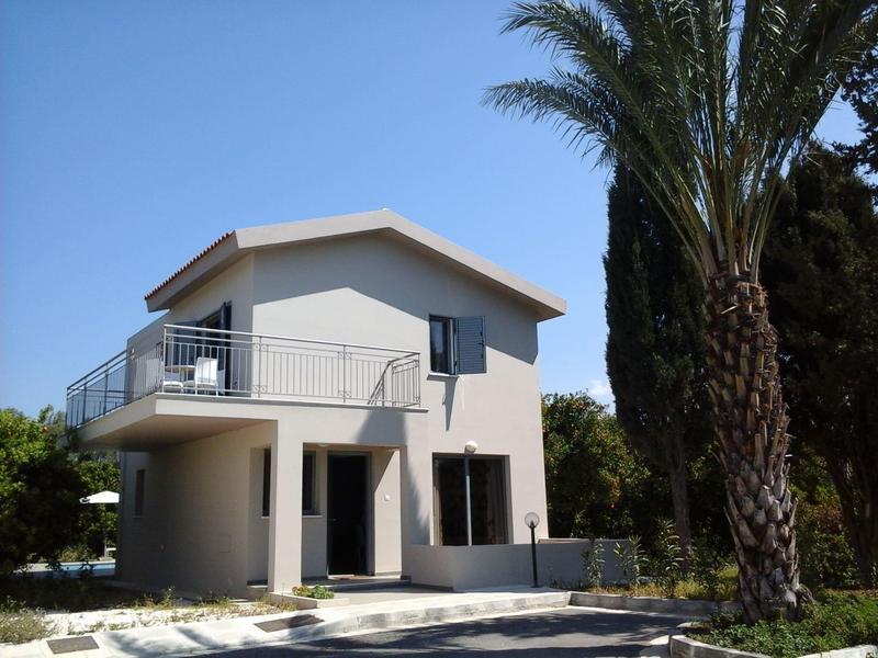 Modernes weißes Haus mit Balkon und großer Palme rechts bei klarem Himmel.