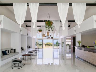 Hall dell'hotel moderno con pareti bianche, panche, piante, luminoso e accogliente.