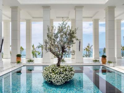 Nowoczesny basen kryty w jasnym, białym pomieszczeniu z roślinami w środku