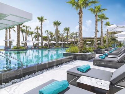 Nowoczesny basen na zewnątrz z leżakami i palmami pod niebieskim niebem w ośrodku.