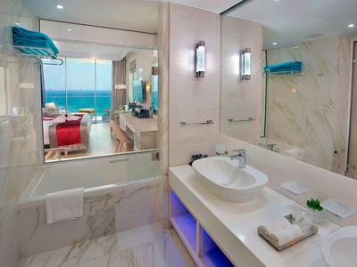 Modernes Badezimmer mit weißer Marmorverkleidung, Doppelwaschbecken und großem Spiegel.