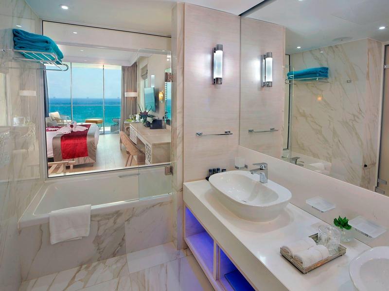 Modernes Badezimmer mit weißer Marmorverkleidung, Doppelwaschbecken und großem Spiegel.