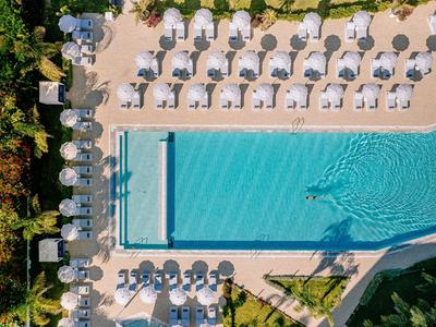 Vue aérienne d'une piscine rectangulaire avec des chaises longues blanches et des parasols.