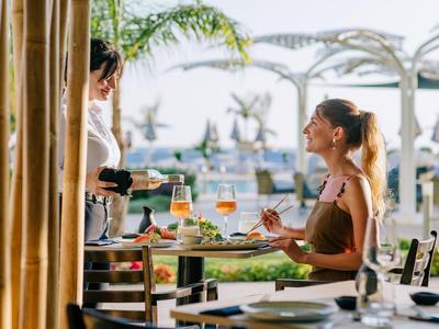 Jeune femme assise à une table dressée en plein air avec vue sur la terrasse.