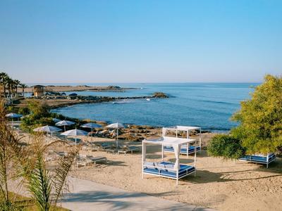 Plage avec sable, auvent et vue sur la mer bleue calme et le ciel dégagé.