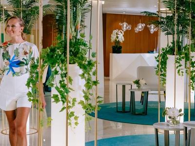 Un couple se tient dans un hall d'hôtel moderne et élégant avec des plantes et des espaces de détente.