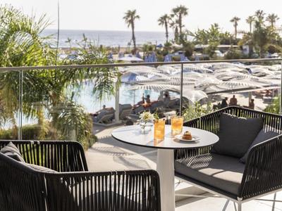 Balcone con tavolo, due sedie, vista su piscina e mare in hotel per vacanze.