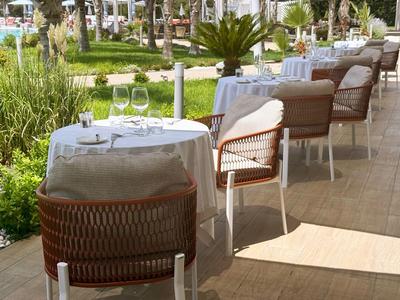 Espace de restaurant extérieur élégant avec des tables nappées de blanc et des chaises en rotin.