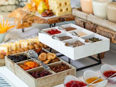 Buffet mit Trockenfrüchten, Nüssen, Käsescheiben und verschiedenen Marmeladen in Schalen.