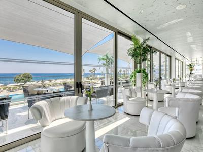 Salon d'hôtel moderne avec fauteuils blancs et vue sur la mer à travers de grandes fenêtres vitrées